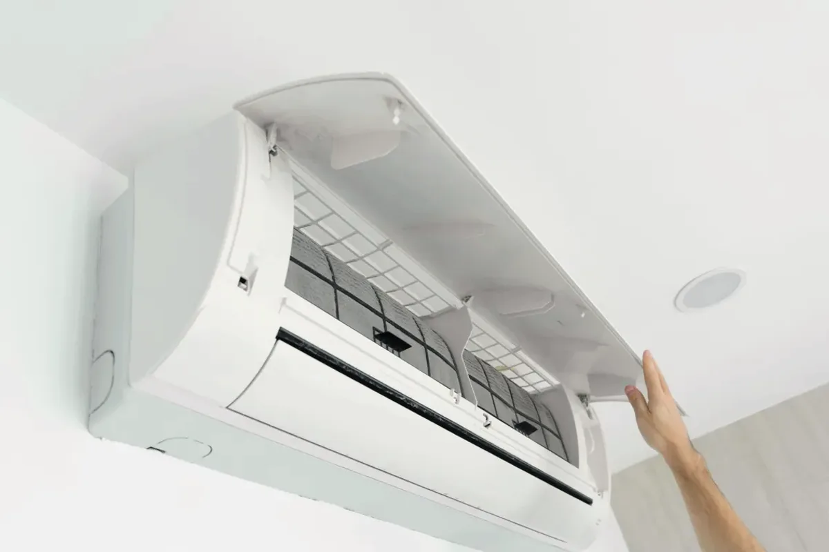 Hand opening the cover of a wall-mounted ductless air conditioner